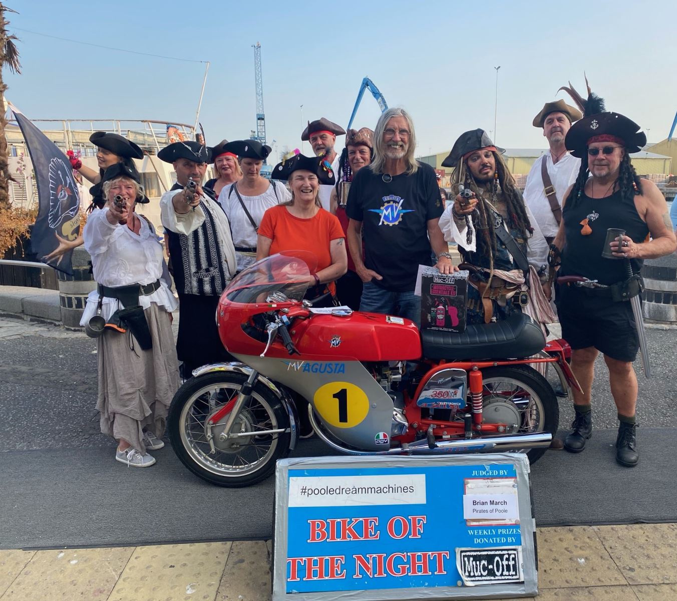 Group of pirates surround the bike of the night winner at Poole quay 